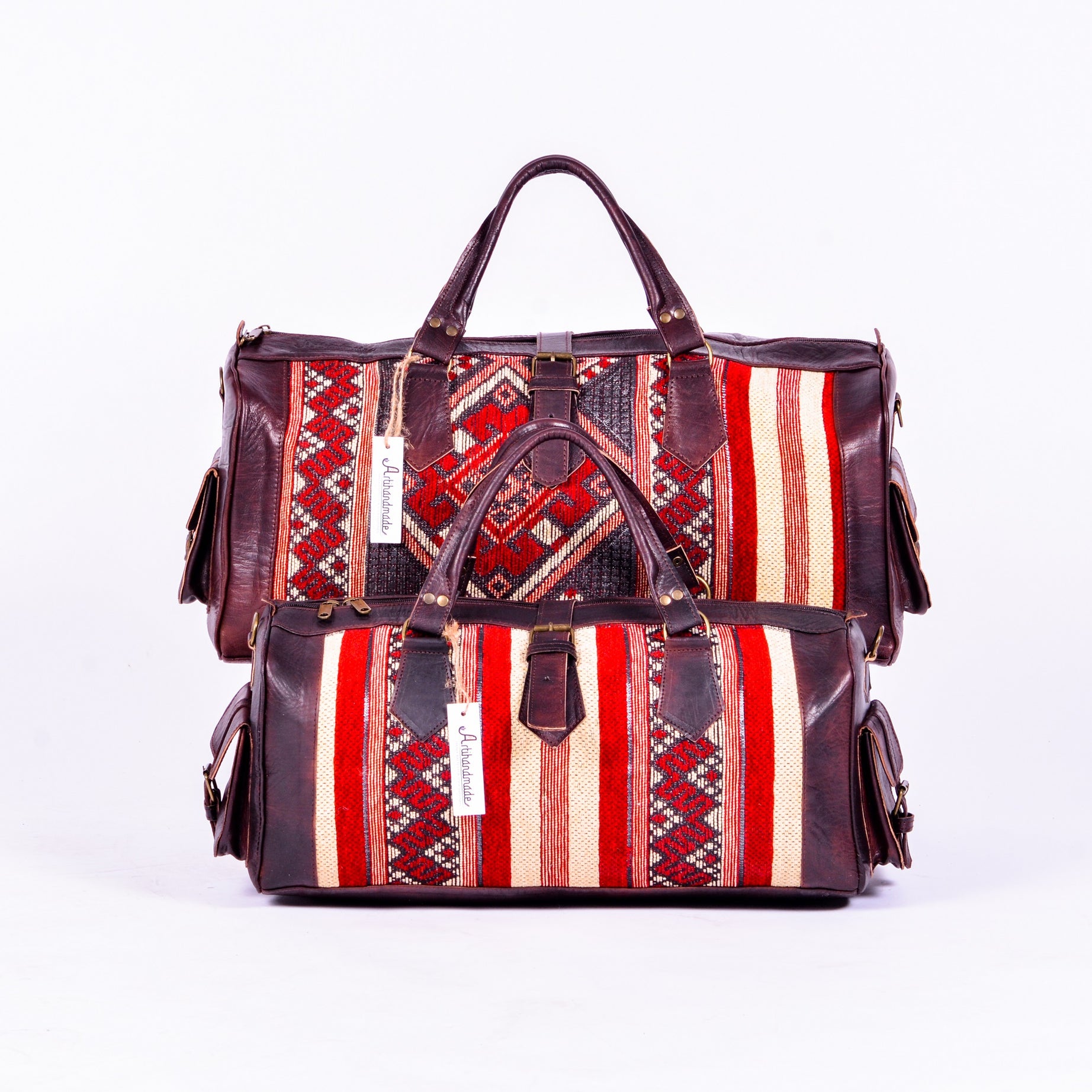 Two duffel bags with a combination of leather and kilim designs, featuring a striped pattern in red, brown, and beige colors, with a leather finish and metal hardware.