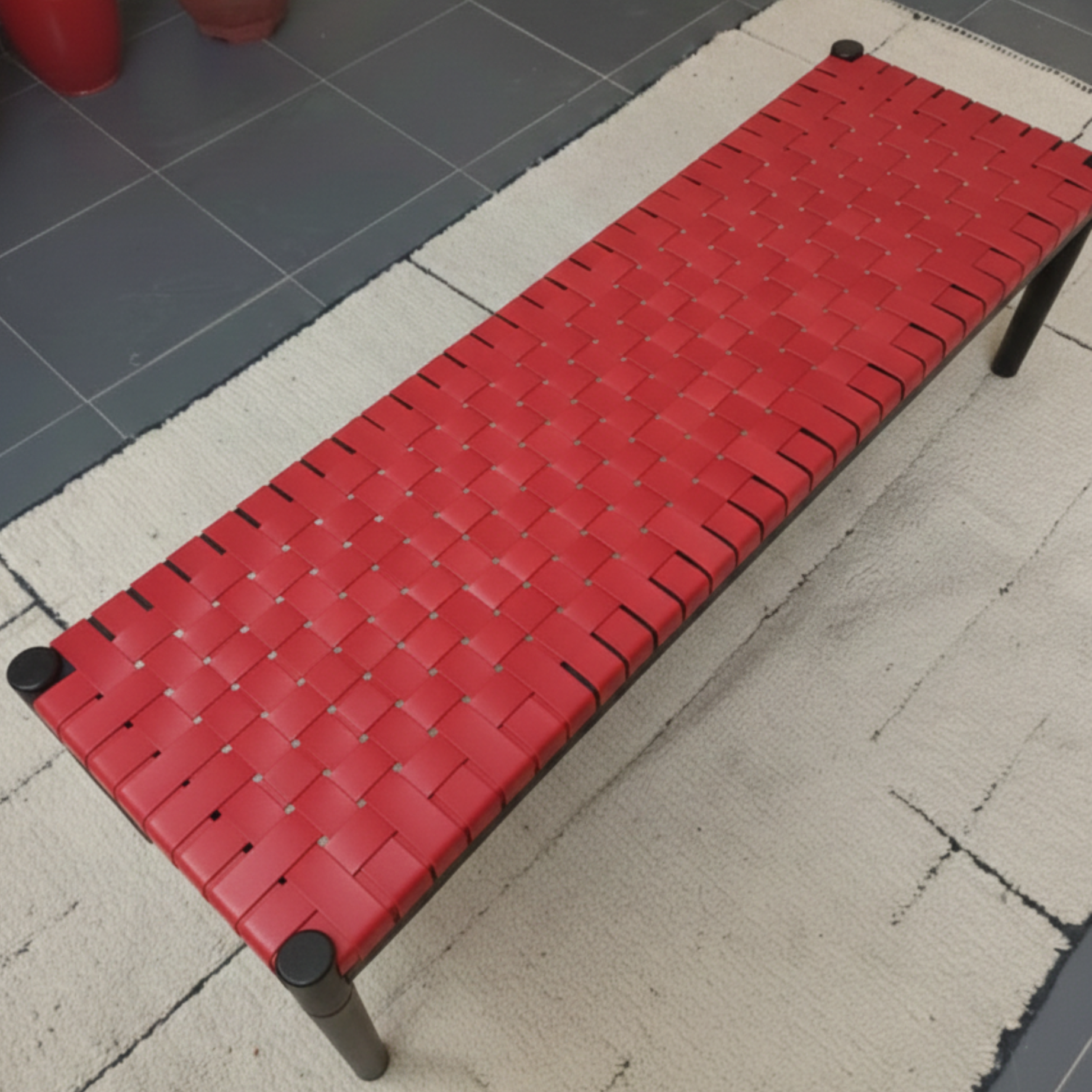Red woven bench on a tiled floor