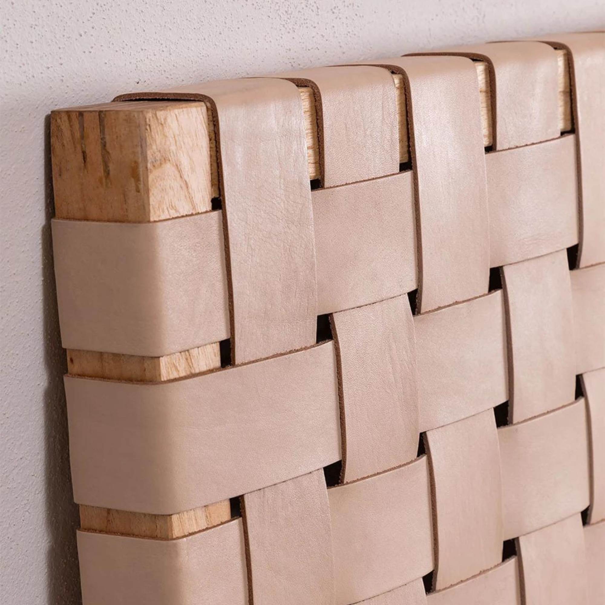 Close-up of handwoven leather strap across solid teak headboard